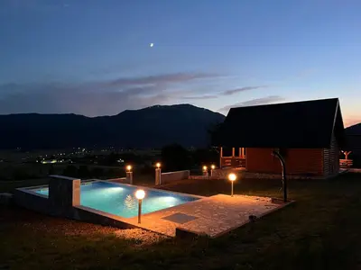 a swimming pool with lights in front of a house at Vikendica Ivana in Livno