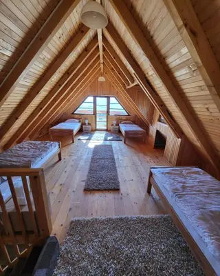 an attic with benches and rugs in a room at Vikendica Ivana in Livno