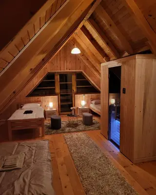 a large attic room with a bed and a table at Vikendica Ivana in Livno