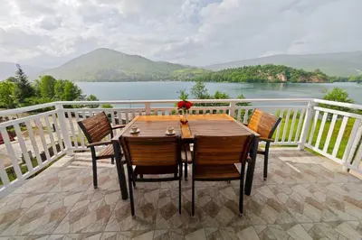 a table and chairs on a deck with a view of a lake at Villa Pliva Lake in Jajce