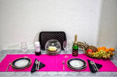 a table with a pink table cloth with wine glasses and fruit at Kingdom Rooms Visoko in Visoko