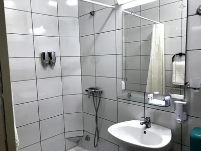 a white tiled bathroom with a sink and a shower at Kingdom Rooms Visoko in Visoko