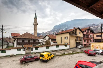 a city with cars parked in a parking lot with a mosque at Kingdom Rooms Visoko in Visoko