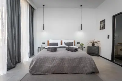 a bedroom with a large bed and large windows at Urban city apartment in Visoko