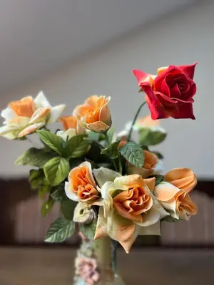 a vase filled with orange and white roses at Bijeli Cvijet in Glamočani