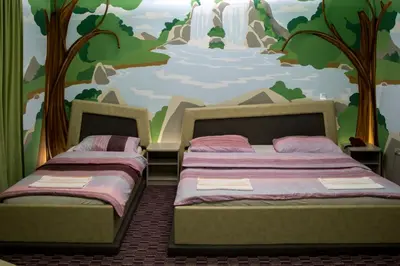 two beds in a bedroom with a mural of a waterfall at Motel Dani in Nova Bila