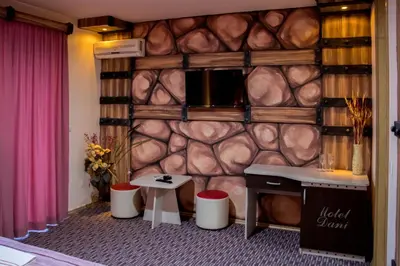a room with a rock wall with a desk and stools at Motel Dani in Nova Bila