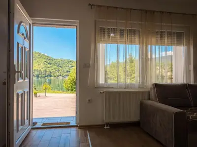 a living room with a couch and a large window at Villa Pliva Lake 2 in Jajce
