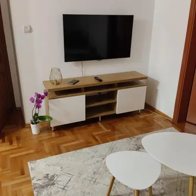 a living room with a tv and two white chairs at Ananbi in Banja Luka