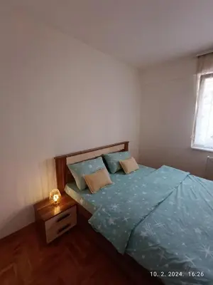 a bedroom with a bed with blue sheets and a window at Ananbi in Banja Luka