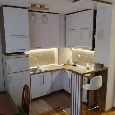 a small kitchen with white cabinets and a table at Ananbi in Banja Luka