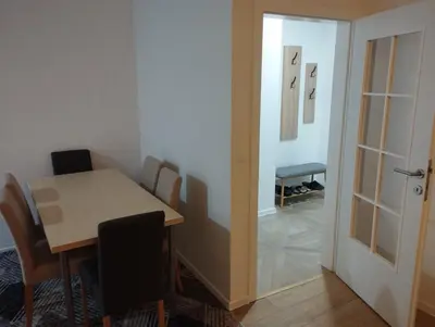 a dining room with a table and chairs and a door at Apartman Nona in Kupres