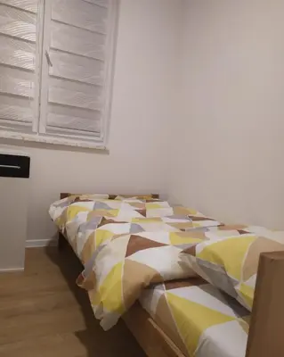 a bedroom with a bed with a yellow and white comforter at Apartman Nona in Kupres