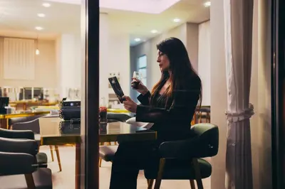 a woman sitting at a table with a glass of wine at Wellness Spa Hotel Jola in Banja Luka