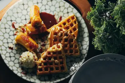 a plate of food with waffles and other foods on a table at Wellness Spa Hotel Jola in Banja Luka