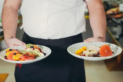 a man holding two plates of food in his hands at Wellness Spa Hotel Jola in Banja Luka