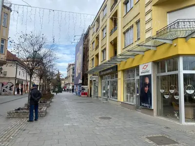 a man standing on a street in front of a building at Apartman Centar E&A in Tuzla