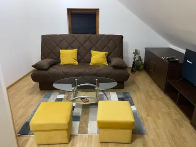 a living room with a brown couch and yellow pillows at Apartman Centar E&A in Tuzla