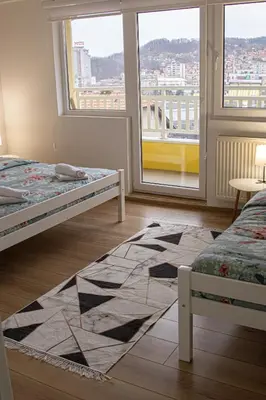 a bedroom with two beds and a large window at Apartment Forever in Tuzla