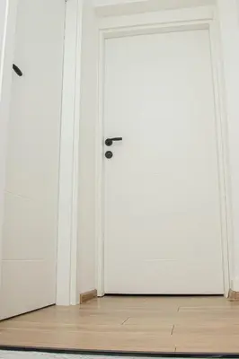 an open white door in a room with a wooden floor at Apartment Forever in Tuzla