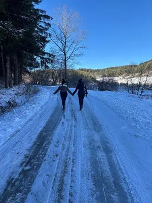 two people walking down a snow covered road holding hands at Apartment Znaor in Kupres