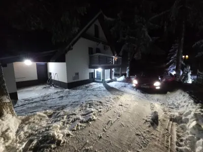 a car parked in a snow covered yard at night at Apartman Flora Vlasic in Vlasic