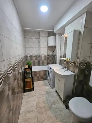a bathroom with a sink and a washing machine at Apartman Ema Tuzla in Tuzla
