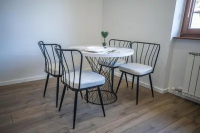 a dining room table with four chairs and a table with a plate on it at E&A Apartman Ajla i Amir in Tuzla