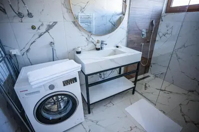 a bathroom with a washing machine and a sink at E&A Apartman Ajla i Amir in Tuzla
