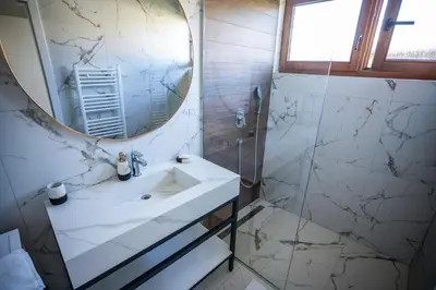 a white bathroom with a sink and a mirror at E&A Apartman Ajla i Amir in Tuzla