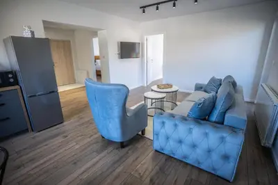 a living room with a blue couch and a table at E&A Apartman Ajla i Amir in Tuzla