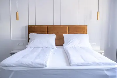 a bed with white sheets and pillows on it at E&A Apartman Ajla i Amir in Tuzla