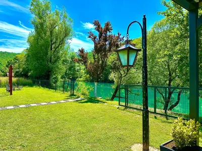 a lamp post in the grass next to a body of water at Aqua Vita Concept in Bihać