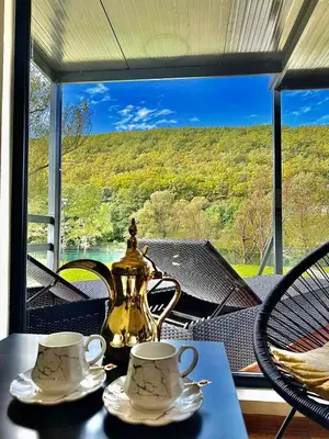 a tea kettle and two cups on a table in front of a window at Aqua Vita Concept in Bihać