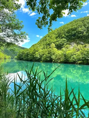 a lake in the middle of a mountain with trees at Aqua Vita Concept in Bihać