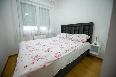 a bedroom with a bed with pink flowers on it at Apartman Mihalena in Banja Luka