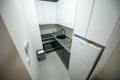a small kitchen with white cabinets and a refrigerator at Apartman Mihalena in Banja Luka
