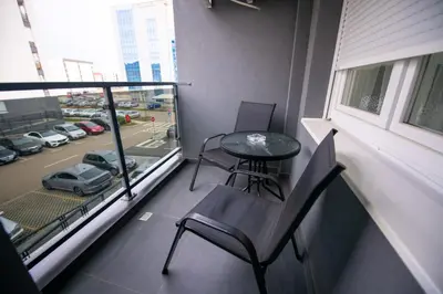 a balcony with a table and chairs and a view of a parking lot at Apartman Mihalena in Banja Luka