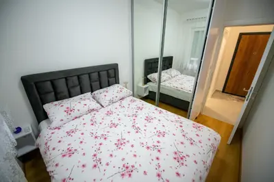 a bedroom with a bed with red flowers on it at Apartman Mihalena in Banja Luka
