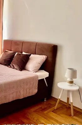 a bed with a brown headboard and a side table at Apartman A&A in Banja Luka
