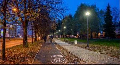 two people walking down a sidewalk in a park at night at Apartman A&A in Banja Luka