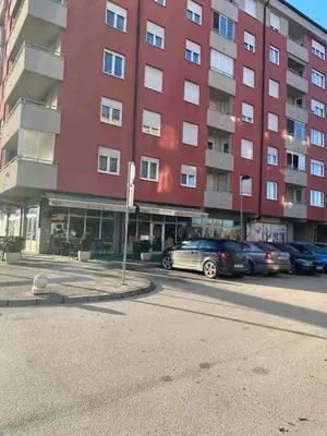 a red building with cars parked in a parking lot at Apartman A&A in Banja Luka