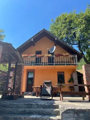 a house with a balcony and a table and a bench at Bed and Breakfast Family Djukic in Šipovo