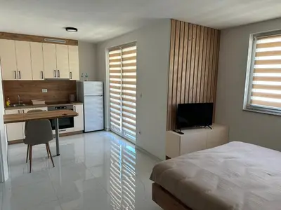 a bedroom with a bed and a desk and a kitchen at Apartmani Marković in Doboj