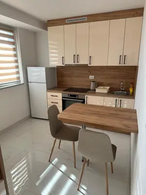 a kitchen with a wooden table and two chairs at Apartmani Marković in Doboj