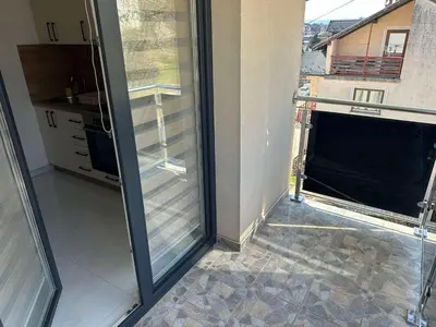 an empty room with a sliding glass door with a kitchen at Apartmani Marković in Doboj