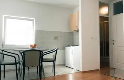 a kitchen with a table and chairs and a refrigerator at Apartman Oskar 2 in Kupres