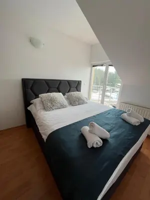 a bedroom with a large bed with two towels on it at Apartman Oskar 2 in Kupres