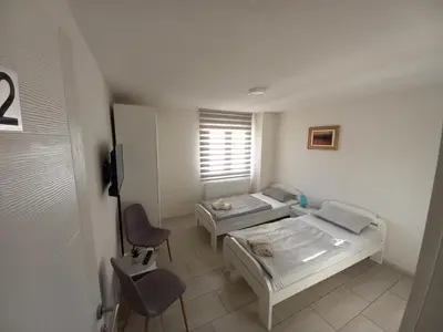 a room with two beds and a chair and a window at SOBE CICKO in Bosansko Petrovo Selo