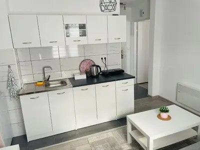 a white kitchen with a sink and a table at Apartment Zara Bihac in Bihać